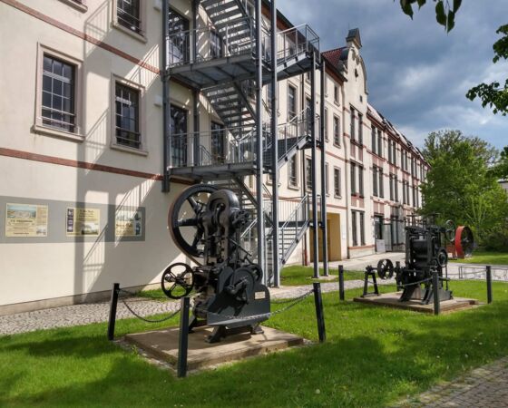 Im Innenhof der Kulturfabrik stehen zwei gewaltige Maschinen, eine Stanze und ein Kalander zum Glätten von Bändern
